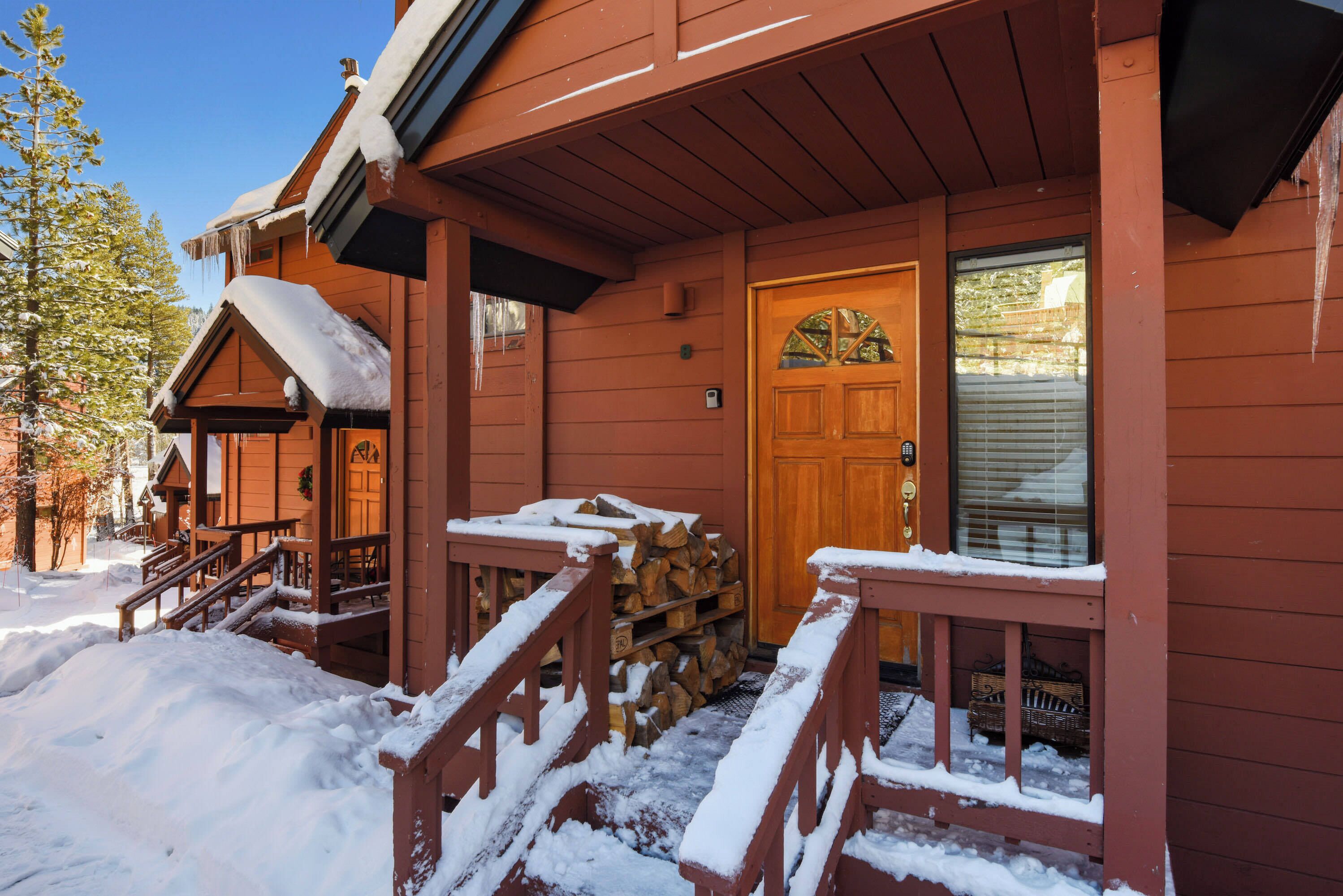 Una construcción de madera con un porche cubierto de nieve, una puerta de madera y una ventana con persianas.
