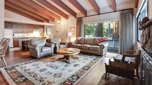 A spacious living room with a fireplace, a large window with curtains, and a kitchen in the background. - Waters Edge Escape Patio w/ Bbq, Near Beach (Tahoma)