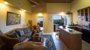 A spacious living area with a sofa, chairs, a coffee table, and a kitchen with a bar. - The Beach Villas w/ Pool Hot Tub & A/c! (Kailua-Kona)