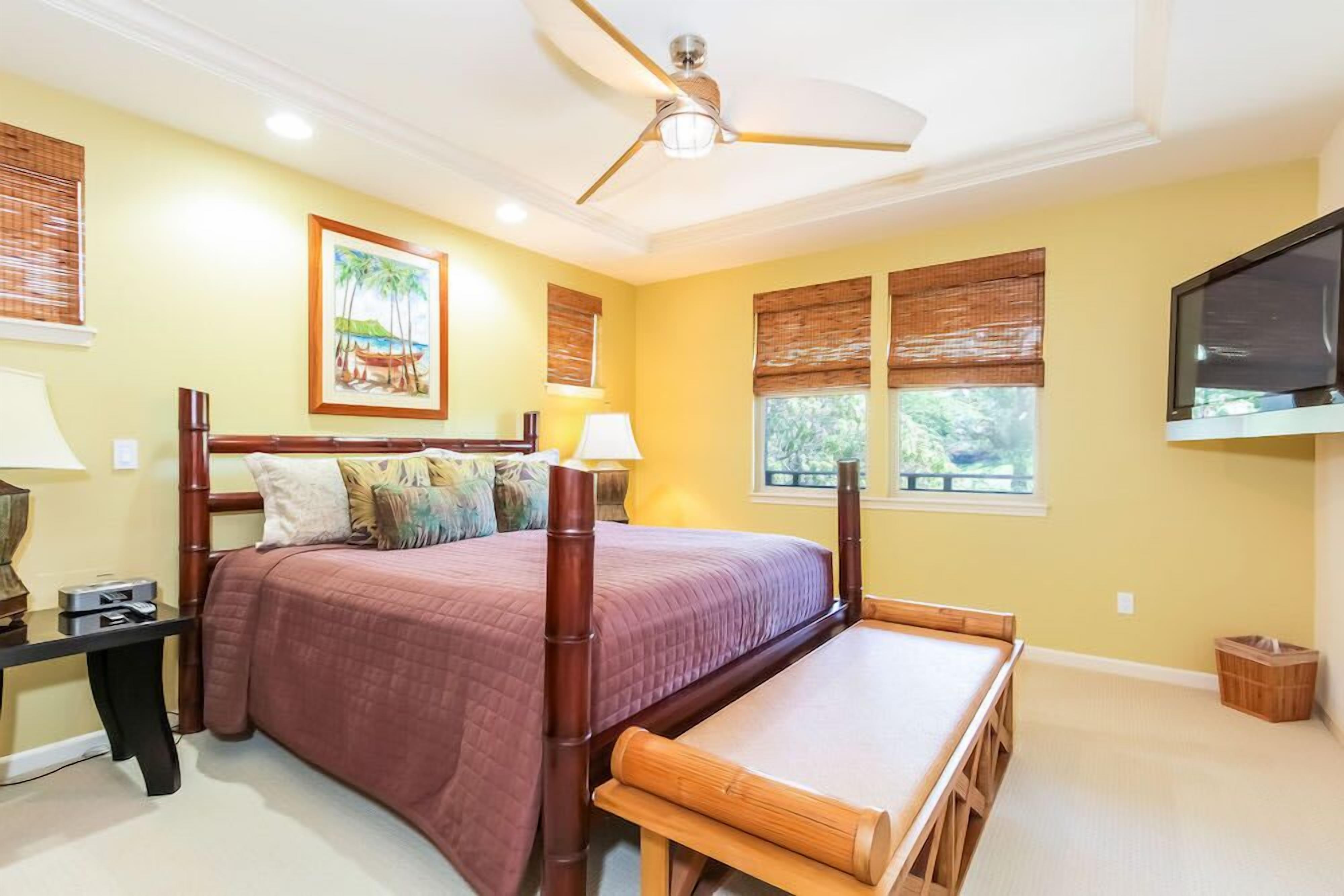 A bedroom with a bed, bedside table, lamp, and a ceiling fan.