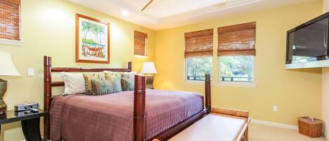 A bedroom with a bed, bedside table, lamp, and a ceiling fan.