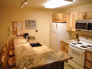 Kitchen features a refrigerator, microwave, stove, sink, and coffee maker.