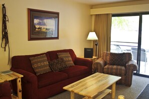 Relax in this inviting space with a sofa, coffee table, and armchair, plus a large window with curtains.
