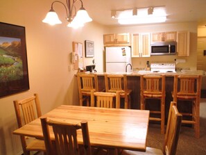 Kitchen area with a central island, refrigerator, stove, sink, and dining table.