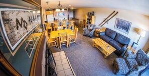 A cozy living area with a dining table, chairs, a sofa, and a bookshelf. - Standard Condo w/ Slope Access (Whitefish)