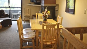 A dining area with a wooden table and chairs, a vase with flowers, and a television on the wall. - Large, Split Level Condo (Whitefish)