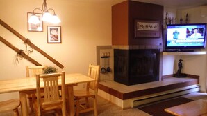 A living room with a fireplace, wooden furniture, and a television mounted on the wall. - Comfortable Condo Near Slopes (Whitefish)