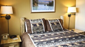 A room with a bed, two bedside lamps, a painting of a lake, and a telephone on a wooden nightstand. - Comfortable Condo Near Slopes (Whitefish)