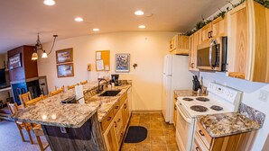 Una cucina moderna con piani di lavoro in granito, mobili in legno, un forno a microonde integrato e un fornello.
