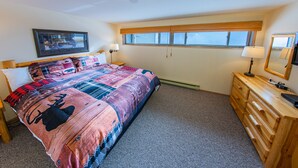 Un dormitorio con una cama grande, un aparador de madera, un televisor y una ventana con persianas.