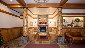 Eine Lobby mit Kamin aus Stein, Holzsäulen und einem Weihnachtsbaum.