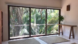 A room with large sliding glass doors, a wooden table, and woven mats on the floor.