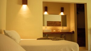 A hotel room with a bed, a bathroom with a sink and mirror, and a door leading to another room.