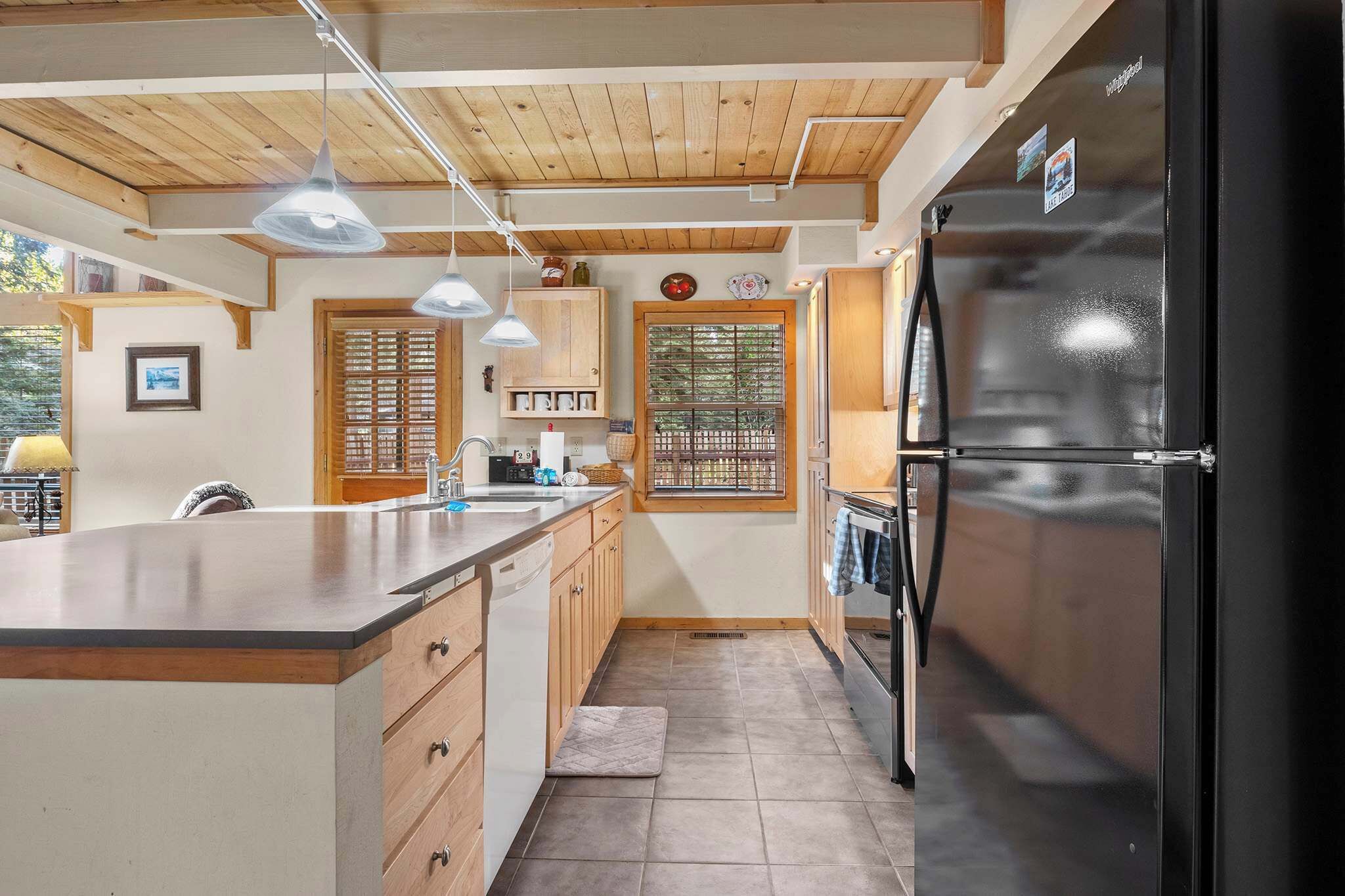 Una cocina moderna con armarios de madera, un refrigerador negro e iluminación colgante.