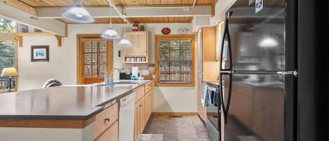 Una cocina moderna con armarios de madera, un refrigerador negro e iluminación colgante.