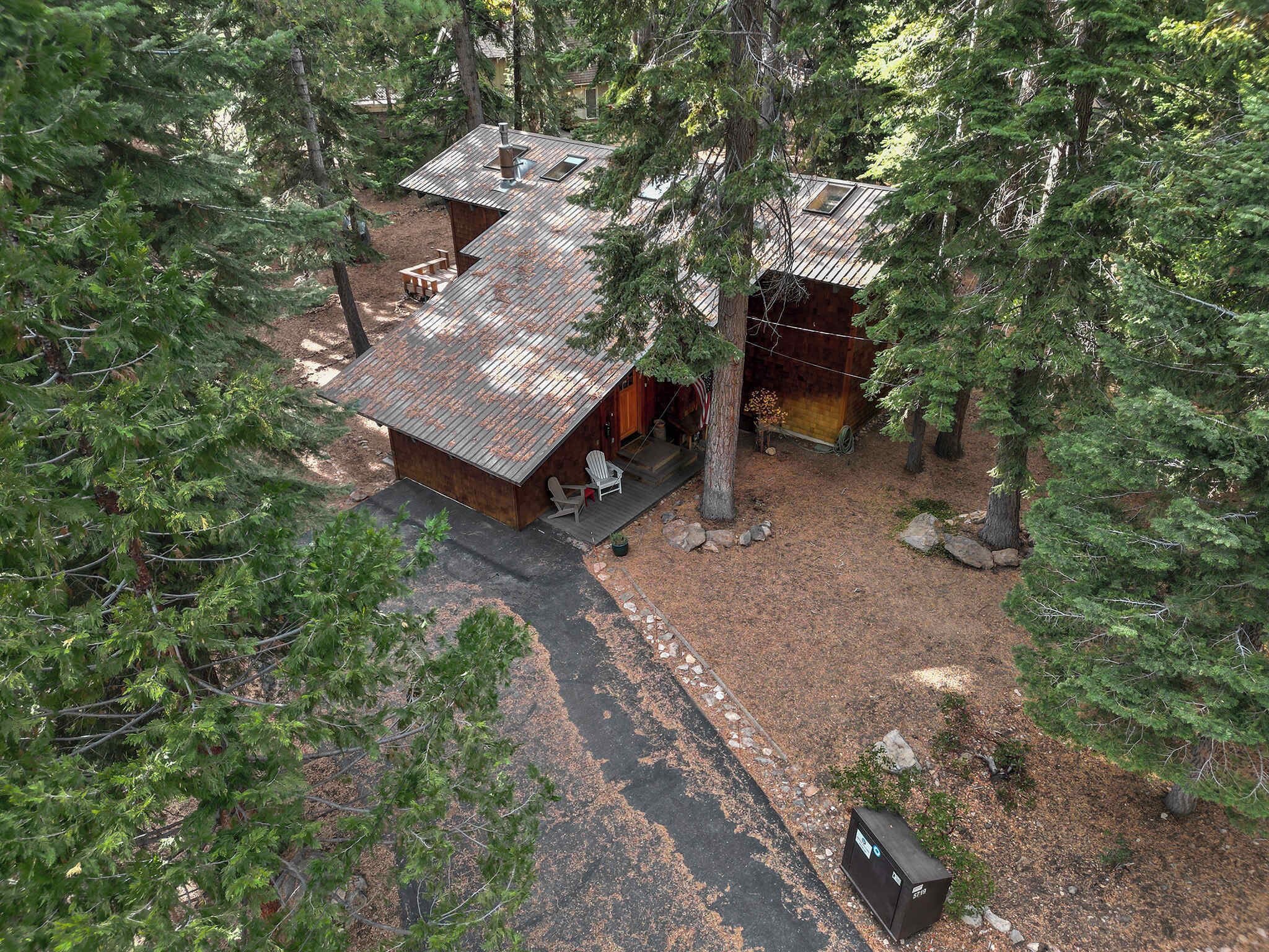 A cabin with a metal roof, surrounded by trees.