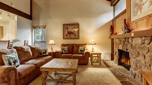 A cozy living room with a stone fireplace, leather sofas, and a wooden coffee table. - Whiskey Rock (South Lake Tahoe)