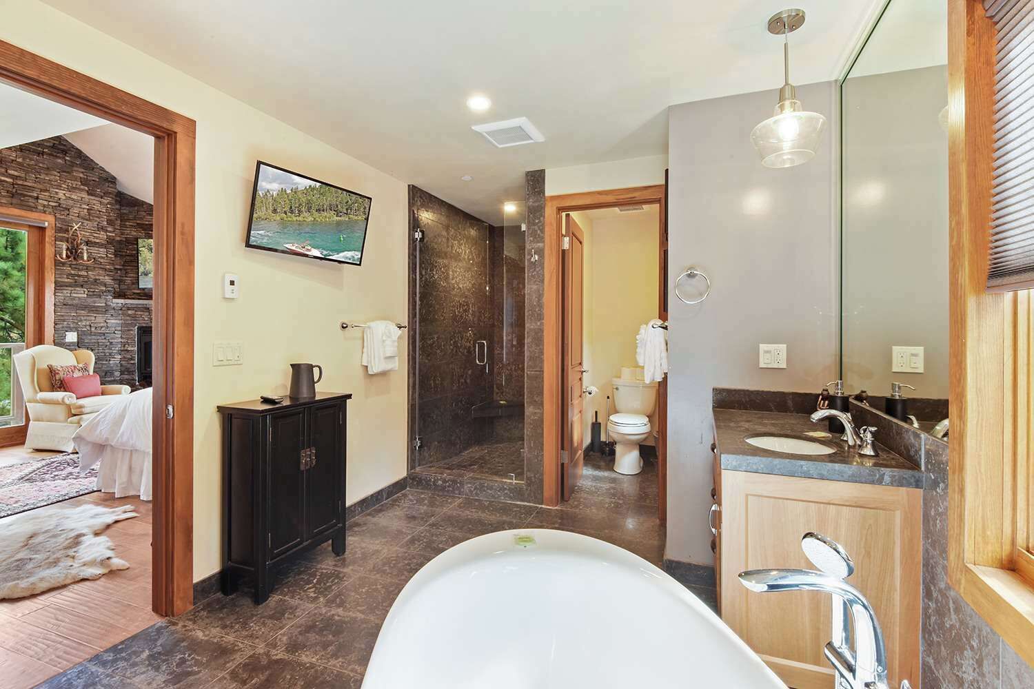 A modern bathroom with a large bathtub, a vanity with a sink, and a shower area.