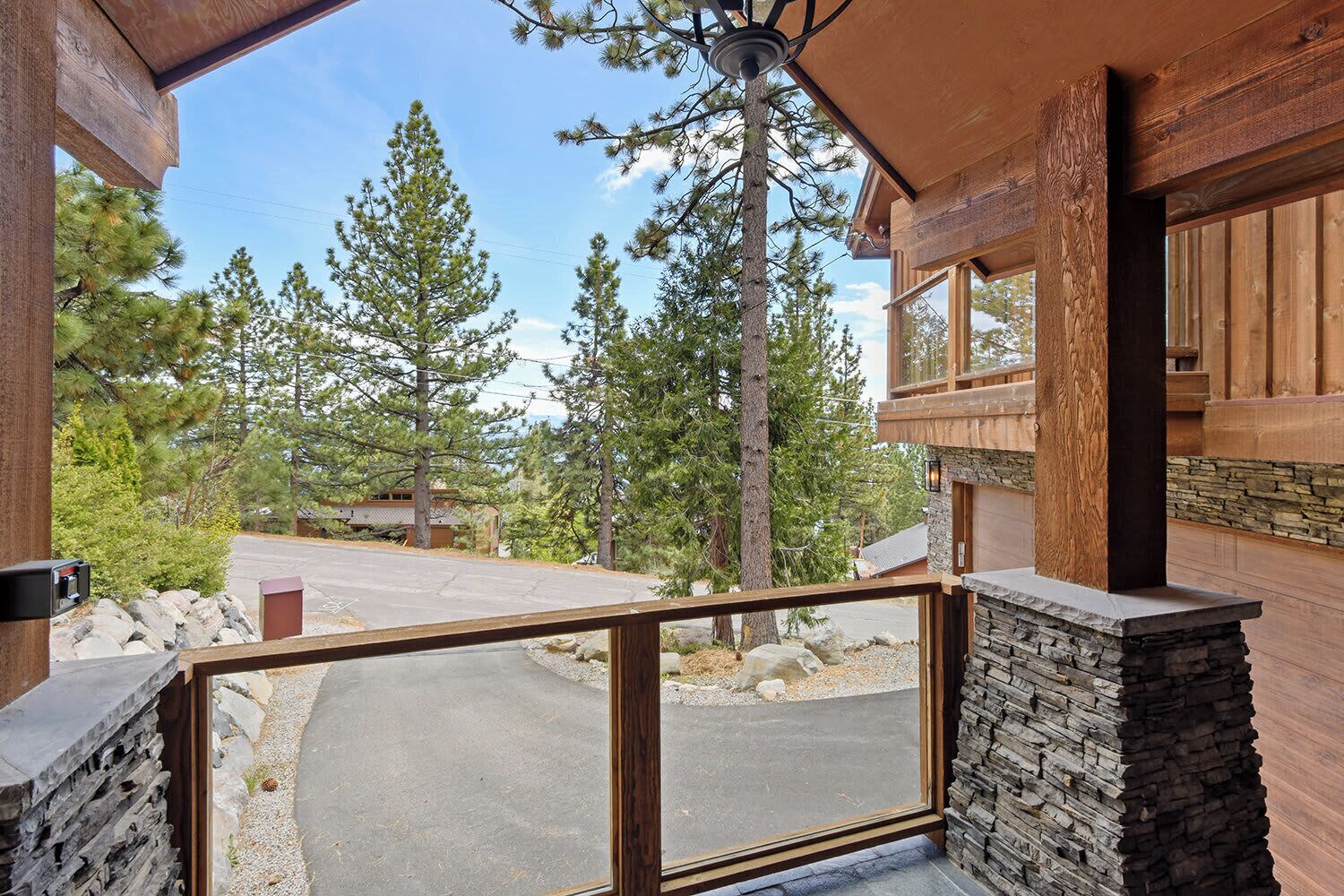 A wooden cabin with a stone foundation, a covered porch, and a view of a forested area.
