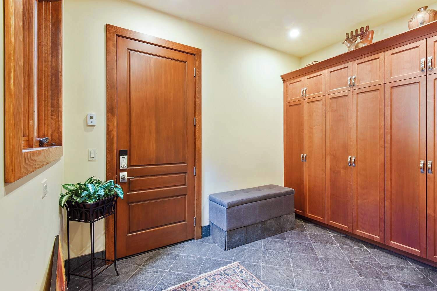 Un pasillo con una puerta de madera, un banco y un armario.