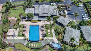 An aerial view of a resort with a central swimming pool, multiple guest villas, and a parking area. - Kolea 11D Walk to the Beach (Waikoloa)