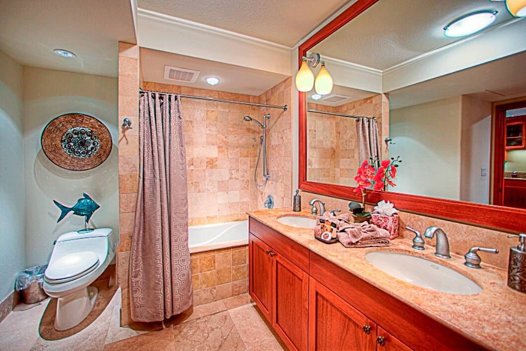 A bathroom with a toilet, bidet, bathtub, and a large mirror.