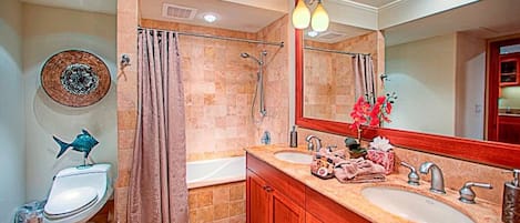 A bathroom with a toilet, bidet, bathtub, and a large mirror.
