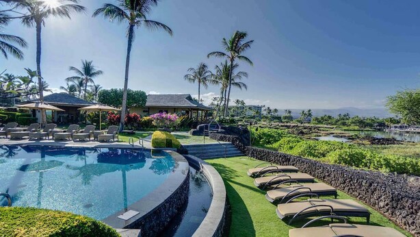 A pool area with lounge chairs, palm trees, and a view of the landscape. - Kolea 11D Walk to the Beach (Waikoloa)