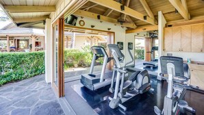 A covered outdoor gym area with exercise equipment, a stone floor, and a wooden ceiling. - Kolea 11D Walk to the Beach (Waikoloa)
