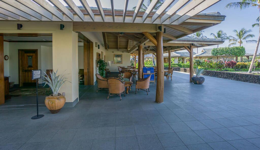 A covered outdoor seating area with wicker furniture and potted plants.