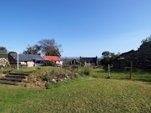 Un paysage rural avec des bâtiments en pierre, un espace clos et un ciel dégagé.