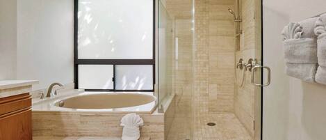 Un baño moderno con una bañera grande, una ducha con cerramiento de vidrio y una ventana que proporciona luz natural.