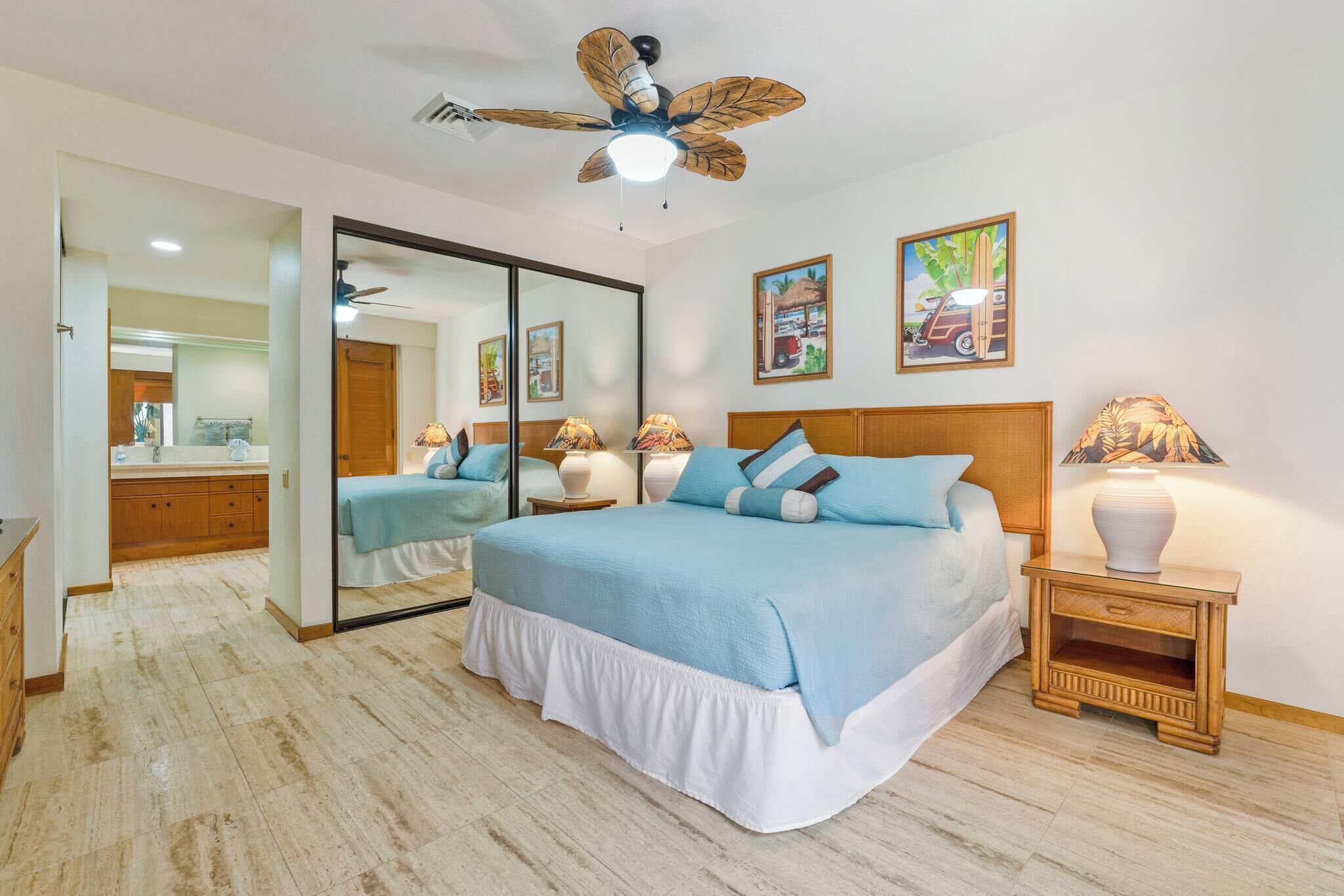 A bedroom with a bed, a ceiling fan, a nightstand, a mirror, and wall art.