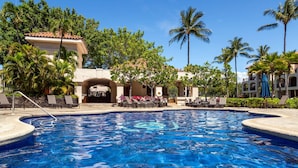 Una piscina con sillas de descanso y palmeras.