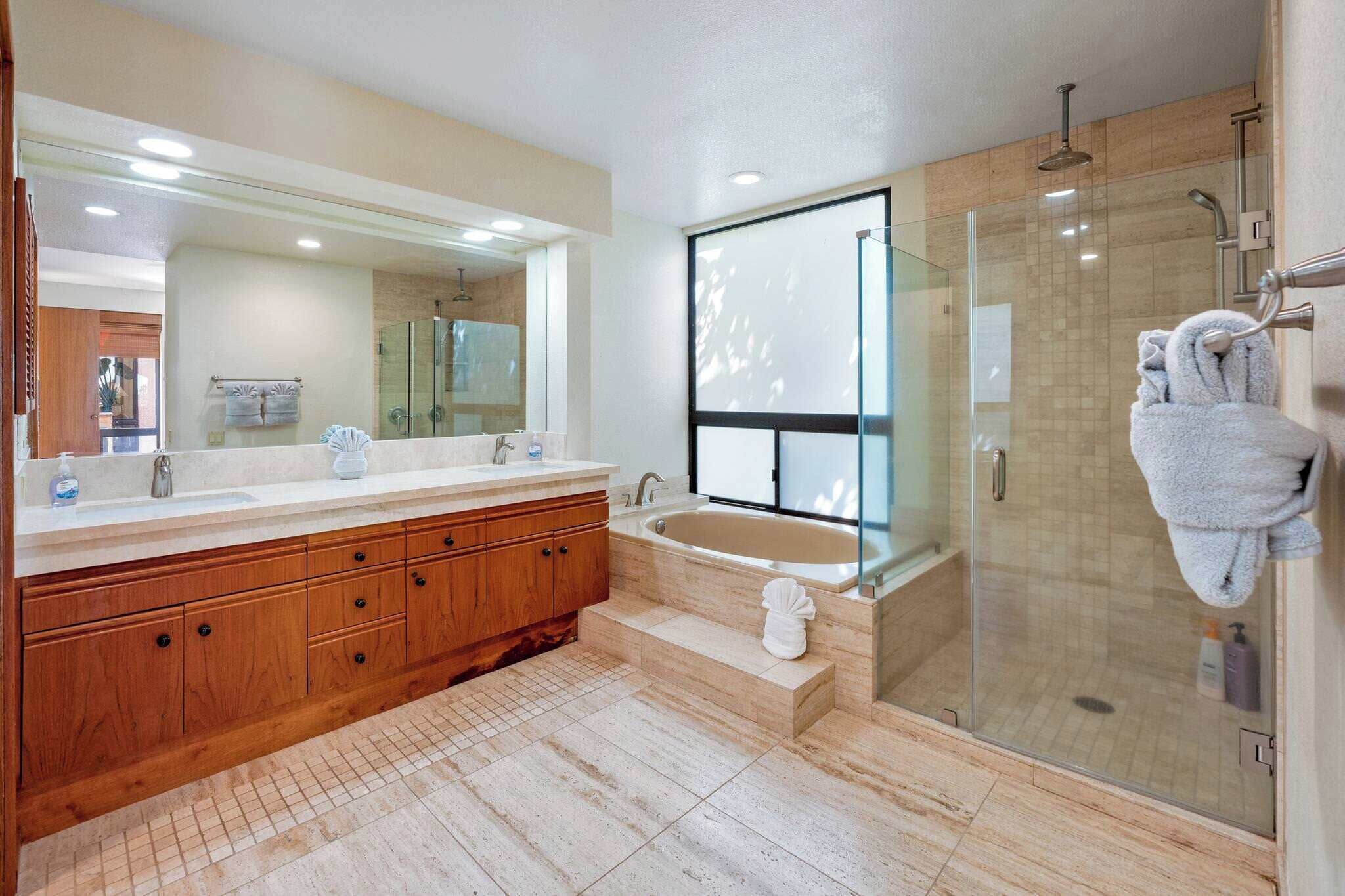 A modern bathroom with a wooden vanity, a large mirror, a glass-enclosed shower, and a bathtub.