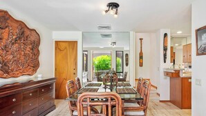 Un comedor con una mesa de vidrio, sillas de madera y un gran elemento decorativo de madera tallada en la pared.
