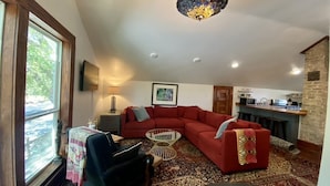 A living room with a red sectional sofa, a black armchair, a patterned rug, a round coffee table, and a chandelier. - Cozy Cool Apartment on 6th Street!
WALK TO ACL FEST! (Austin)