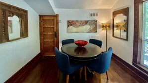 A dining area with a round table, blue chairs, and a red bowl. There are two wall-mounted lamps and a large painting above the table. - Cozy Cool Apartment on 6th Street!
WALK TO ACL FEST! (Austin)