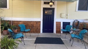 A covered patio area with a black door, blue chairs, and a hanging light fixture. - Cozy Cool Apartment on 6th Street!
WALK TO ACL FEST! (Austin)