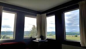 A room with two large windows, a red sofa, and a small table with a tray. - Ramada by Wyndham Florenceville (Florenceville-Bristol)