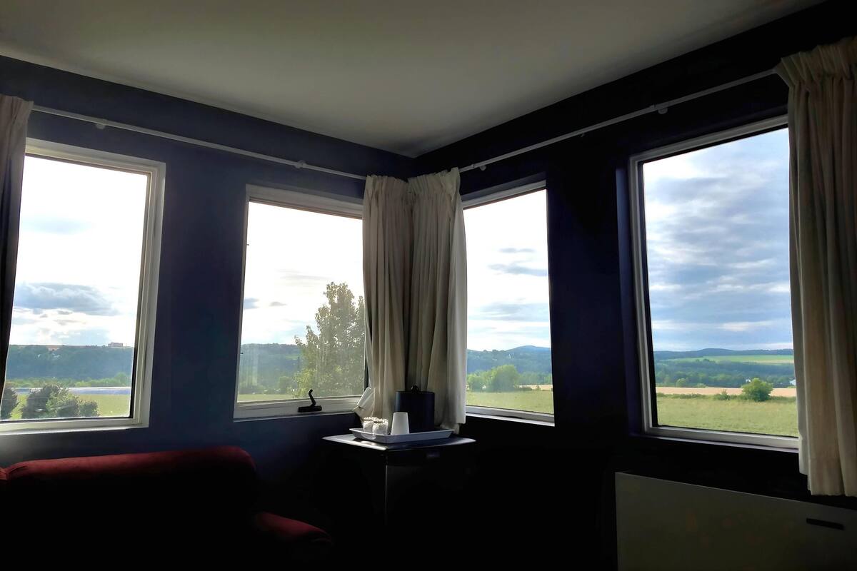 A room with two large windows, a red sofa, and a small table with a tray.