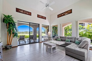 Relax in this stylish living room with a large sofa, coffee table, and armchairs, surrounded by a beautiful view.