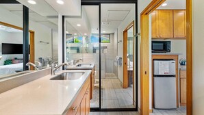 A modern bathroom with a glass shower enclosure, a sink with a mirror, and a toilet. - Exclusive Single-story Shores Golf Villa 20 - 3 Ensuite (Waikoloa)