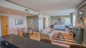Un grand espace de vie comprenant un canapé, une table à manger et des chaises, un coin cuisine avec une cuisinière, et une chambre avec un lit et une table de chevet.