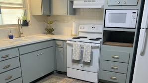 A modern kitchen with grey cabinets, a white stove, a microwave, and a refrigerator.