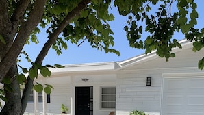 A single-story house with a front porch, a black door, and a white garage door.