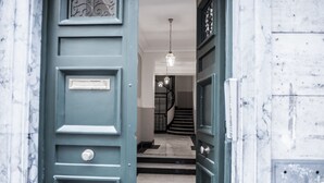 A hallway with a blue door, a staircase, and a hanging light fixture. - Spagna Boutique Luxury Suites (Rome)