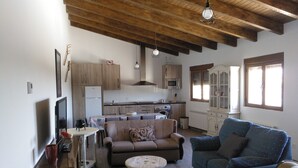 A cozy living room with a wooden ceiling, a dining area, and a kitchen. - La Carrascala rural house 2 (Villaseco del Pan)