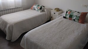 Two single beds with patterned bedspreads, a bedside table with a telephone, and a radiator. - La Carrascala rural house 2 (Villaseco del Pan)