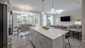 A modern kitchen with a central island, dining area, and living space.